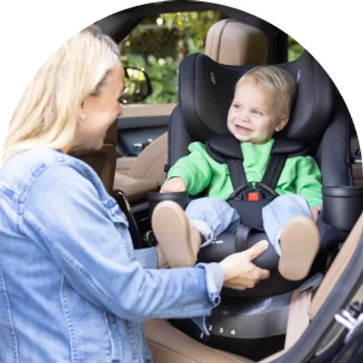Parent smiling at a toddler buckled into a car seat