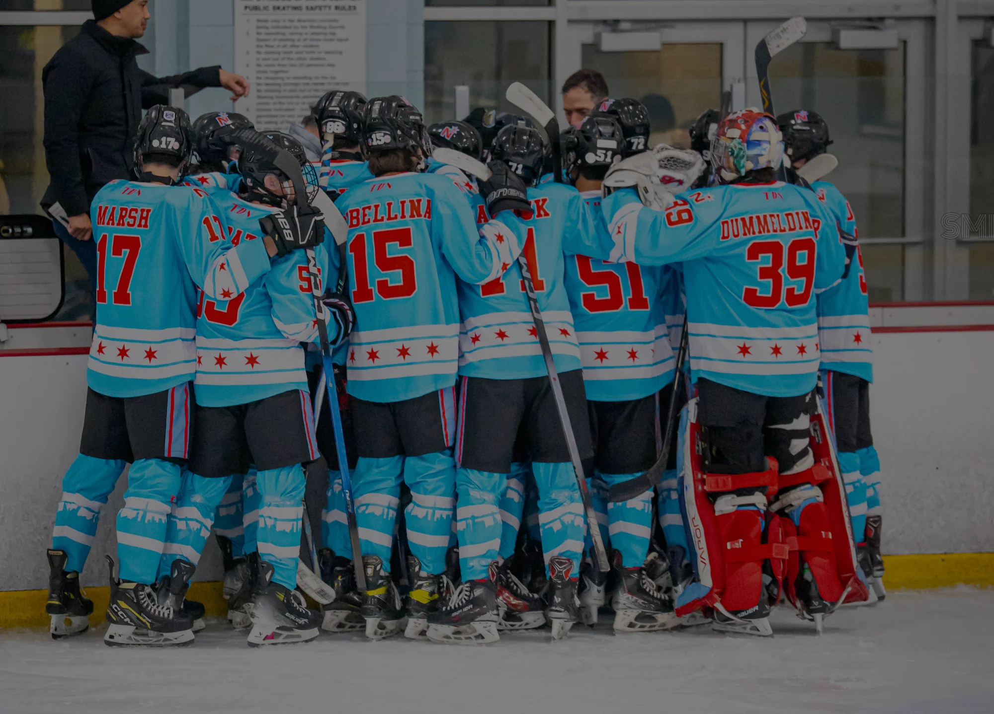 A hockey team huddled together in matching custom teal Handcrafted Hockey jerseys